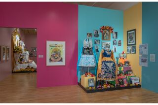 A colorful Serigraph depicting an Ofrenda next to an Altar displaying blue children's dresses, photographics, flowers and papeles picados.