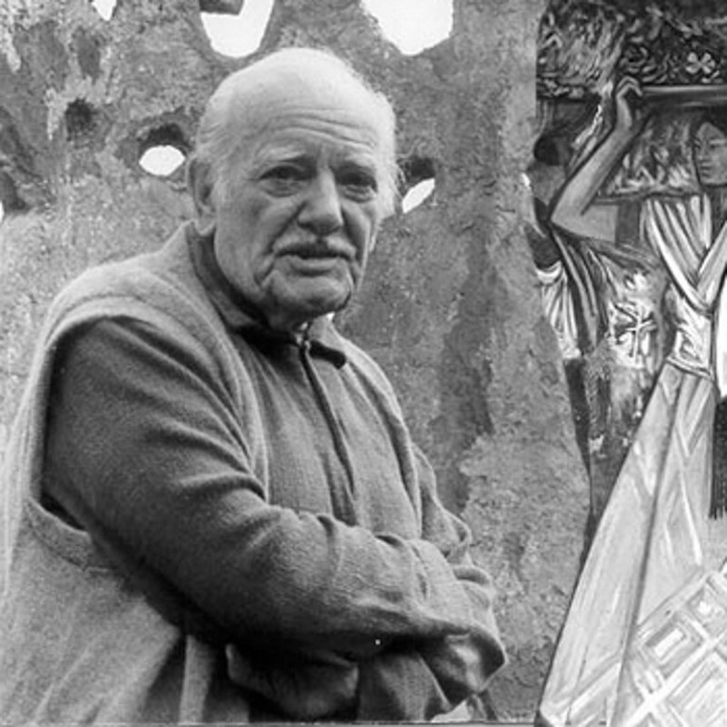 A man wearing a vest poses in front of a painting