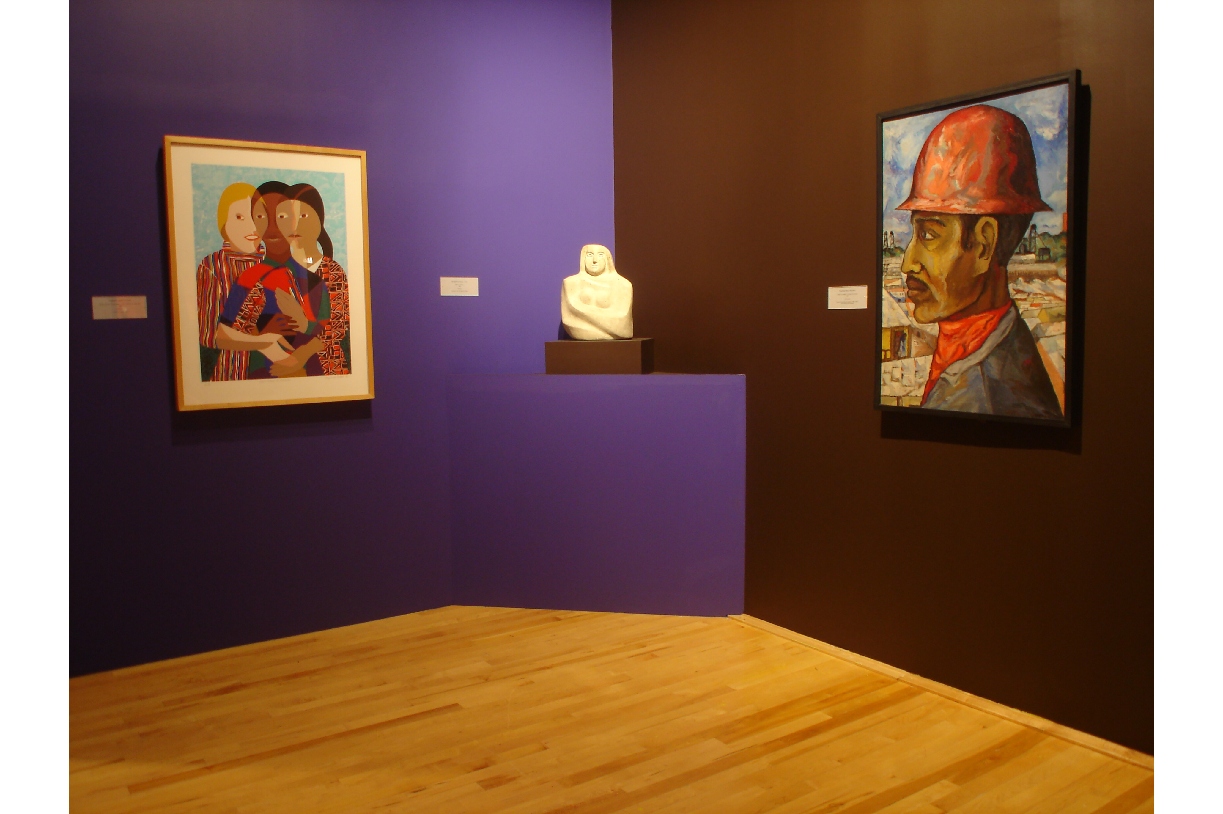 Close image of two gallery walls, with a painting on each wall and a sculpture in the corner in between them
