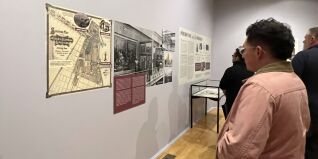 A person in a pink jacket reads wall text about the exhibition.