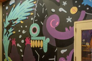 a black and colorful mural in on the walls of the museum gallery